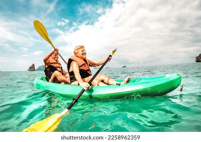 Happy retired couple enjoying travel moment paddling on kayak at Angthong marine park in Ko Samui in Thailand - Active elderly concept around world nature wonders - Bright vivid filtered tone - Powered by Shutterstock