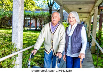 Happy retired couple with stick and walker in the garden.