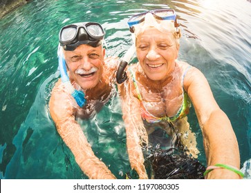 Happy Retired Couple Taking Selfie In Tropical Sea Excursion With Water Camera And Snorkel Masks - Boat Trip Snorkeling In Exotic Scenarios - Active Seniors And Elderly Travel Concept Around The World