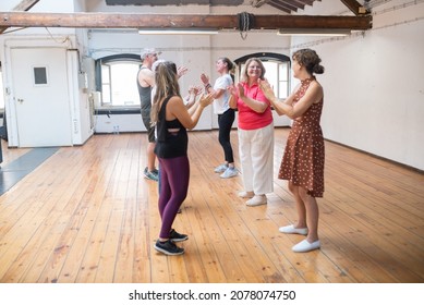 Happy retired dance students clapping their hands with teacher. Group of senior Caucasian dancers clapping hands together with young instructor in dance studio. Dance, hobby, healthy lifestyle concept - Powered by Shutterstock