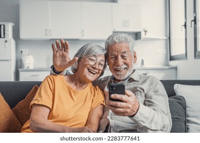 Happy retired family couple using mobile phone for video call together, talking to relations, getting good news, having fun, smiling and laughing. Carefree mature pensioners chatting online on cell