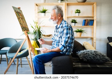 Happy retired man painting on canvas for fun at home - Powered by Shutterstock