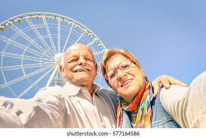 Happy retired senior couple taking selfie at travel around the world - Concept of active playful elderly having fun together - Mature people lifestyle in sunny day with bright midday color tones - Powered by Shutterstock