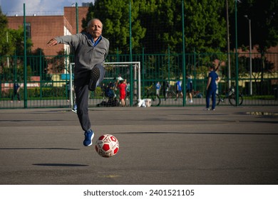 Happy retired senior man kicking a ball playing soccer in a park outside in the afternoon - Powered by Shutterstock