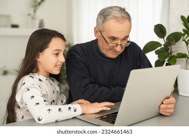 Happy retirement grandfather and pretty granddaughter laughing while watching e-book for learning to education together by laptop. Family educational at home concept. Technology and education. - Powered by Shutterstock