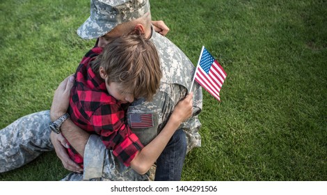 Happy Reunion Of Soldier With Family Outdoors. Father With His Son Hugging, Holiday, Homecoming, Emotions, Happiness