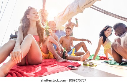 Happy rich friends doing boat party in caribbean sea - Young people having fun drinking beer and listening music in tropical sea tour - Youth, summer and vacation concept - Focus on left girl face