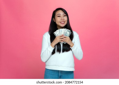 Happy Rich Young Asian Girl Holding Cash Banknotes, Enjoy Money Win, Big Financial Profit And Wealth On Pink Background