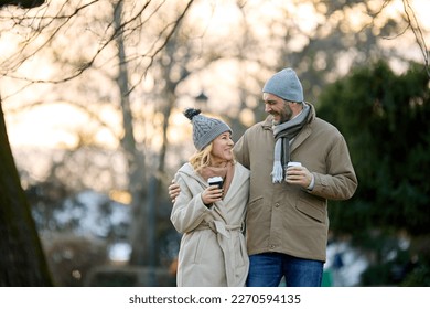 A happy romantic couple with coffee walking in the park - Powered by Shutterstock