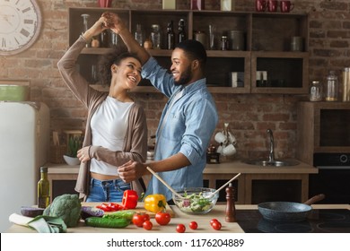 Happy Romantic Couple Dancing In Kitchen While Cooking Together