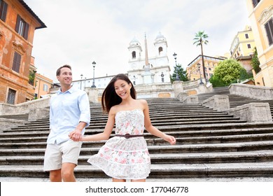 Happy Romantic Couple Holding Hands On Spanish Steps In Rome, Italy. Joyful Young Interracial Couple Walking On The Travel Landmark Tourist Attraction Icon During Their Romance Europe Holiday Vacation