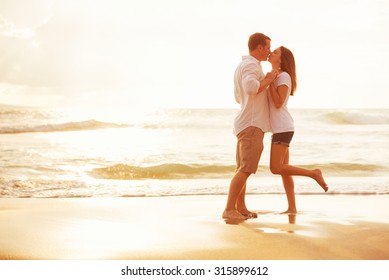 Happy Romantic Couple Kissing On The Beach At Sunset