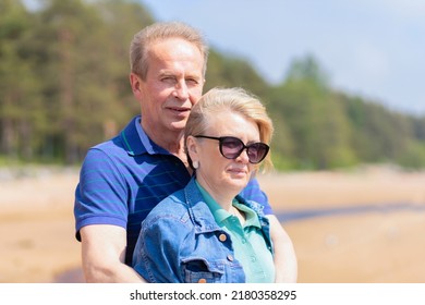 Happy Romantic Mature Adult Couple Family Walking On Beach, Hugging, Smiling, Breathing Fresh Air. Middle Aged Man And Woman Together On Coast