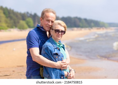 Happy Romantic Mature Adult Couple Family Walking On Beach, Hugging, Smiling, Breathing Fresh Air. Middle Aged Man And Woman Together On Coast