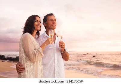 Happy Romantic Mature Couple Drinking Champagne On The Beach At Sunset. Vacation Travel Retirement Anniversary Celebration.