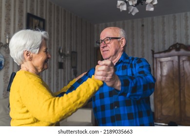 Happy Romantic Old Married Couple Smiling And Dancing In The Living Room, Holding Hands, Having Fun At Home. High Quality Photo