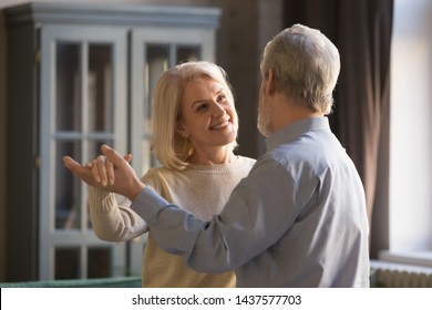 Happy Romantic Old Senior Couple Dancing Waltz At Home, Healthy Mature Grandparents Enjoy Tender Moment Of Love In Slow Dance, Smiling Elder Middle Aged Family Spouses Relaxing Bonding Together