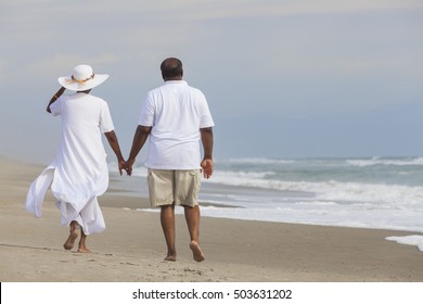 Happy romantic senior African American man and woman couple walking holding hands on a deserted tropical beach 