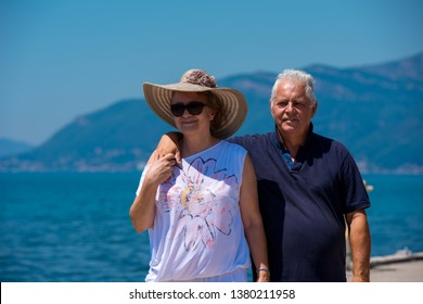 Happy Romantic Senior Couple Hugging While Walking  By The Sea During Summer Vacation