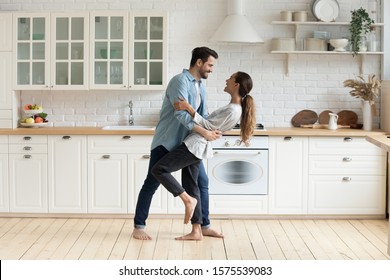 Happy romantic young couple bonding dancing in modern kitchen with white furniture enjoy sweet moments of affection, cheerful husband and wife celebrating anniversary having fun at home lifestyle - Powered by Shutterstock