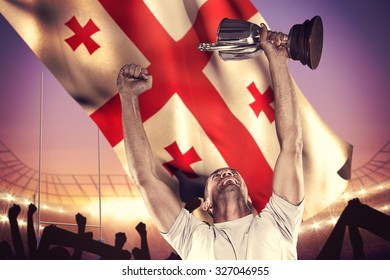 Happy rugby player holding trophy against rugby stadium - Powered by Shutterstock