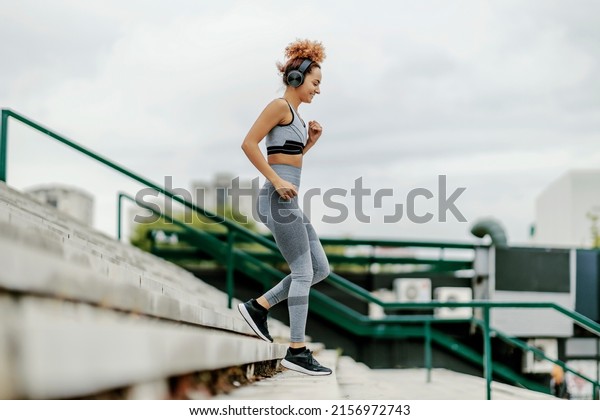 A happy runner listening\
to music and running down the stairs. An urban runner exercising\
outdoor