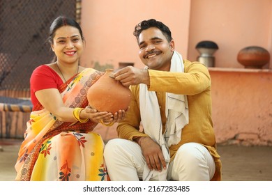 Happy Rural Indian Women In Saree,  Sitting With Husband, Holding The Piggy Bank. Aspirational Family Showing Her Love Towards Their Money Saved And Showing Different Expressions And Emotions Of Life.