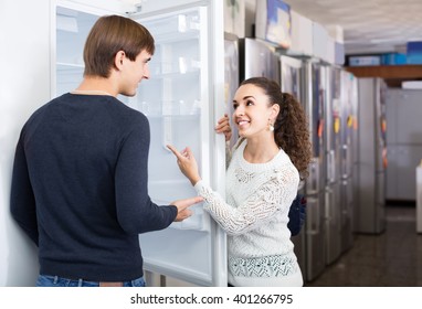 Happy Russian  Family Couple Choosing New Refrigerator In Hypermarket 