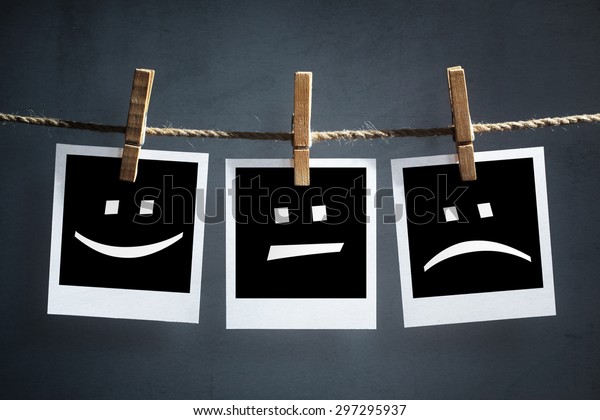 Happy, sad and neutral emoticons\
on instant print transfer photographs hanging on a\
clothesline