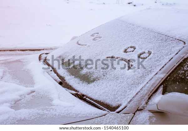 Happy and sad smile emoticon\
face in snow on car windows, winter season joy and happiness\
concept