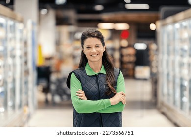 A happy sales manager is proudly standing at the supermarket and smiling at the camera. - Powered by Shutterstock