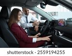 Happy salesman and client inside new car in salon