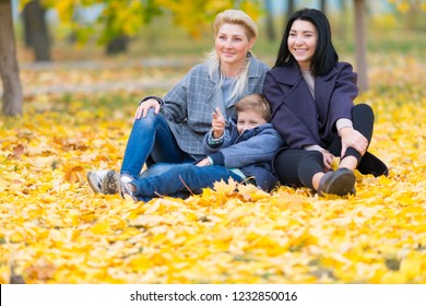 A Happy Same Sex Female Couple And Their Son In A Happy Family Theme With Yellow Fall Leaves.