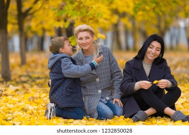 A Happy Same Sex Female Couple And Their Son In An Autumn Park Setting.