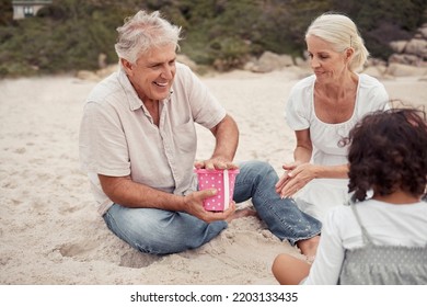 Happy, Sand And Grandparents Playing With Their Grandchildren At The Beach During Summer. Positive Elderly Man And Woman Building Sandcastle With Their Grandkids By The Ocean While On Family Vacation