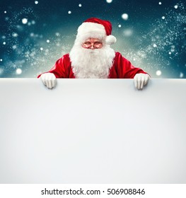 Happy Santa Claus holding blank advertisement banner background with copy space. Smiling Santa Claus pointing in white blank sign. Christmas theme, sales