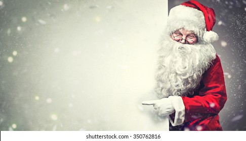 Happy Santa Claus pointing on blank advertisement banner background with copy space. Smiling Santa Claus pointing in white blank sign - Powered by Shutterstock