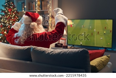 Happy Santa Claus relaxing on the couch and watching a football game on TV
