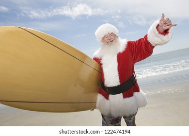 Happy Santa Claus With Surf Board On Beach