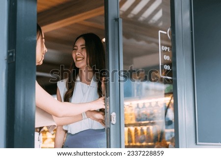 Happy and satisfied Asian customers leaving the restaurant and opening the door on exit. Young adult female consumers finished purchasing from supermarket. - Happy customer concept.