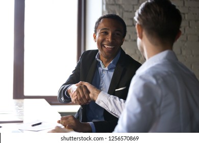 Happy satisfied black client shaking hands thanking manager for good financial deal, african american businessman handshaking partner after successful business negotiations, hiring, buying services