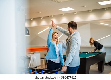 Happy Satisfied Businesspeople Having Fun While Playing Table Football And Pool In A Break.