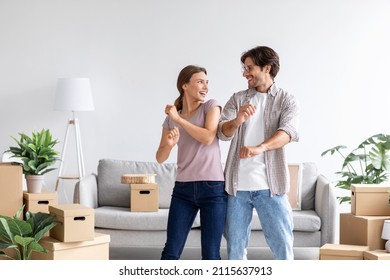 Happy satisfied caucasian man and wife celebrating buying of new apartment, dancing in room interior with cardboard boxes. Couple have fun after moving at own apartment. Rent flat, mortgage and loan - Shutterstock ID 2115637913