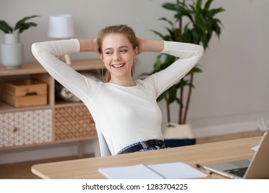 Happy satisfied female student relaxing finished work or study at home, smiling girl holding hands behind head sitting at desk taking break for rest after job well done enjoying no stress free relief