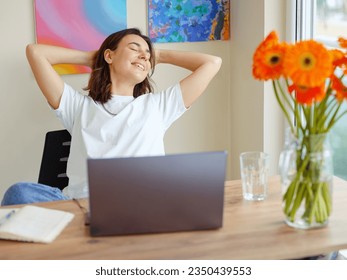 Happy satisfied latin woman rest at home office, sit with laptop hold hands behind head, dreamy young lady relax finished work, feel peace of mind look away , dream think of future success concept