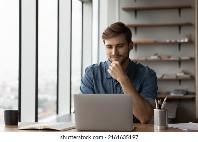 Happy satisfied millennial man using laptop at office workplace, working from home, reading message with good news, thinking, looking at screen, watching online webinar, training, making payment - Shutterstock ID 2161635197