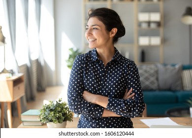 Happy Satisfied Young Indian Woman Student Teacher Freelancer Look Away Dream About Good Future Vision, Smiling Pretty Girl Professional Stand Arms Crossed At Home Hope For New Opportunities Concept