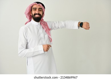 Happy Saudi Arab man smart watch paying Contactless or purchasing and shopping wearing traditional dress using digital technology  - Powered by Shutterstock