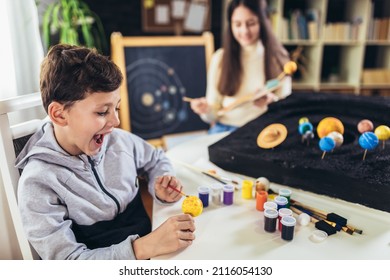 Happy School Boy And Girl  Making A Solar System For A School Science Project At Home