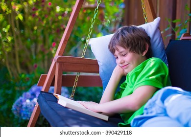 Happy School Boy Reading A Book In The Backyard. Child Relaxing In A Garden Swing With Books. Kids Read During Summer Vacation. Children Studying. Teenager Kid Doing Homework Outdoors.